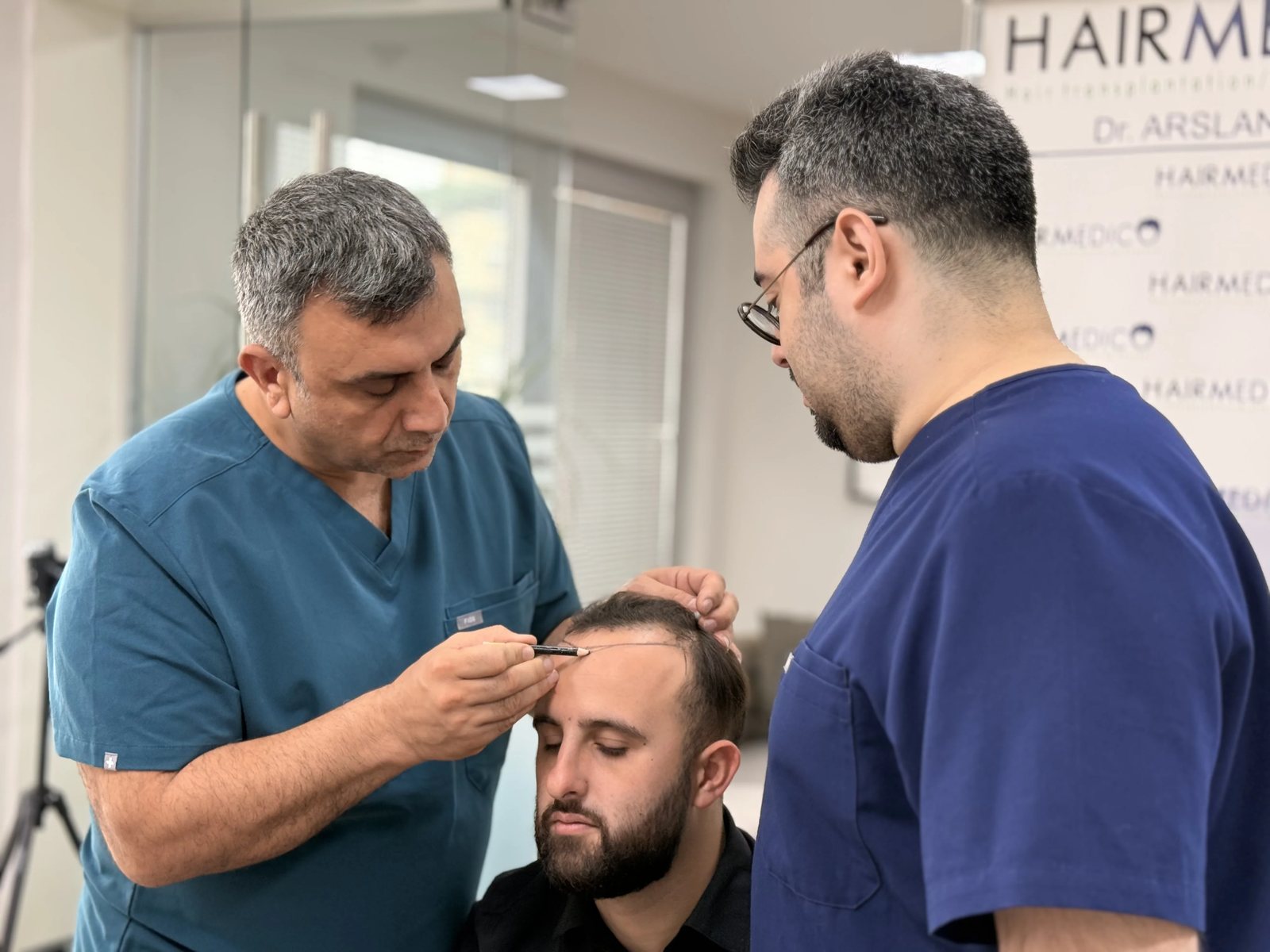 Dr. Arslan Musbeh examining a patient's scalp during consultation