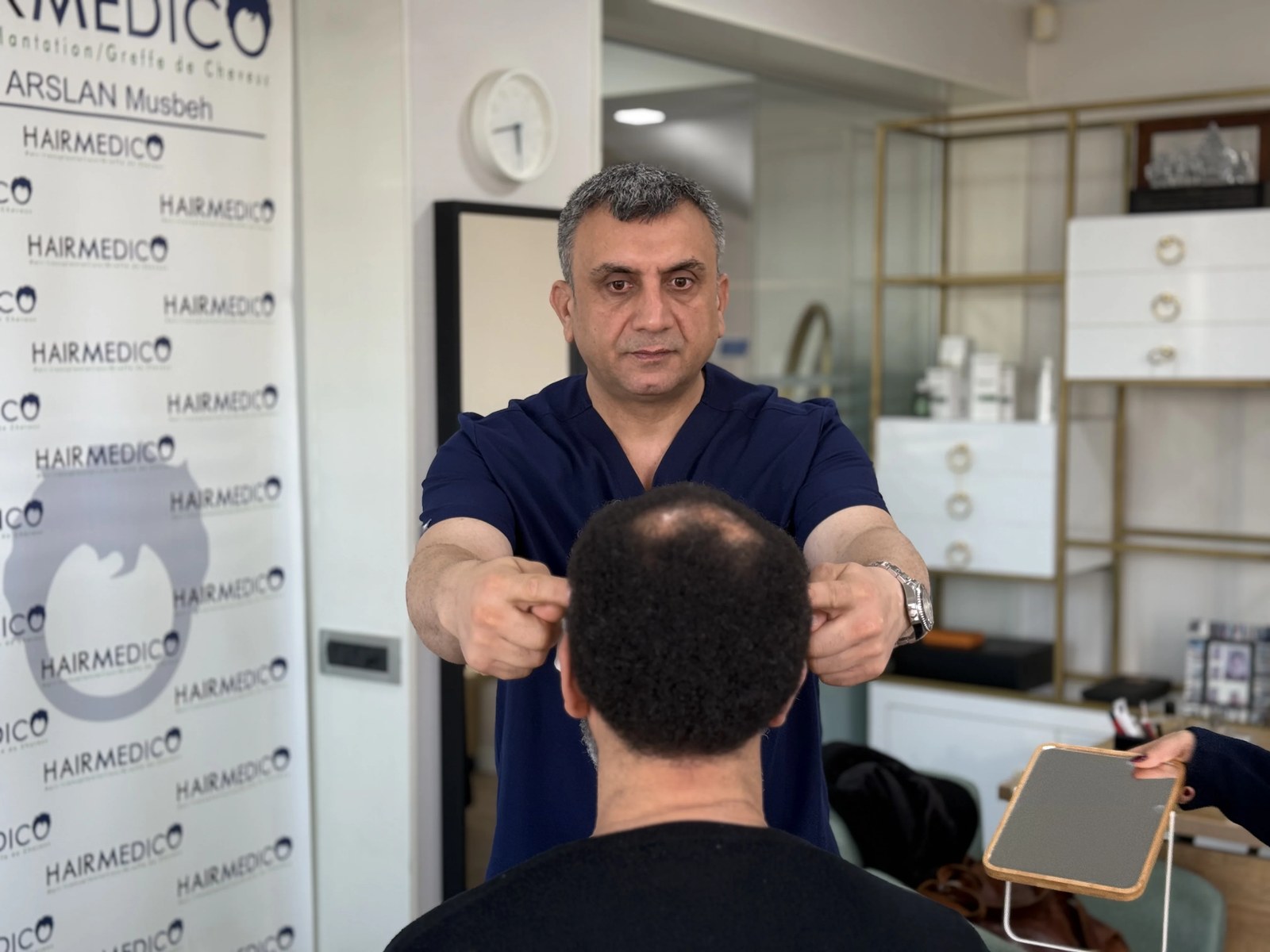 Dr. Arslan Musbeh examining a patient's scalp during consultation