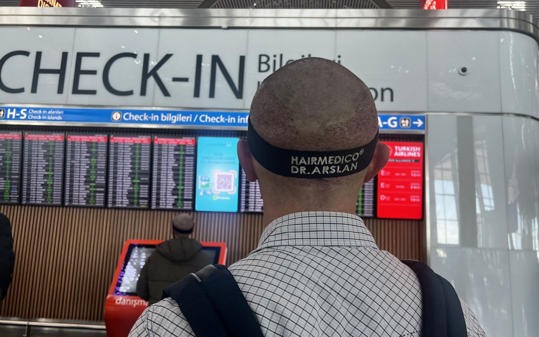 Hairmedico patient wearing a protective post-op headband at Istanbul Airport check-in, flying home after FUE hair transplant